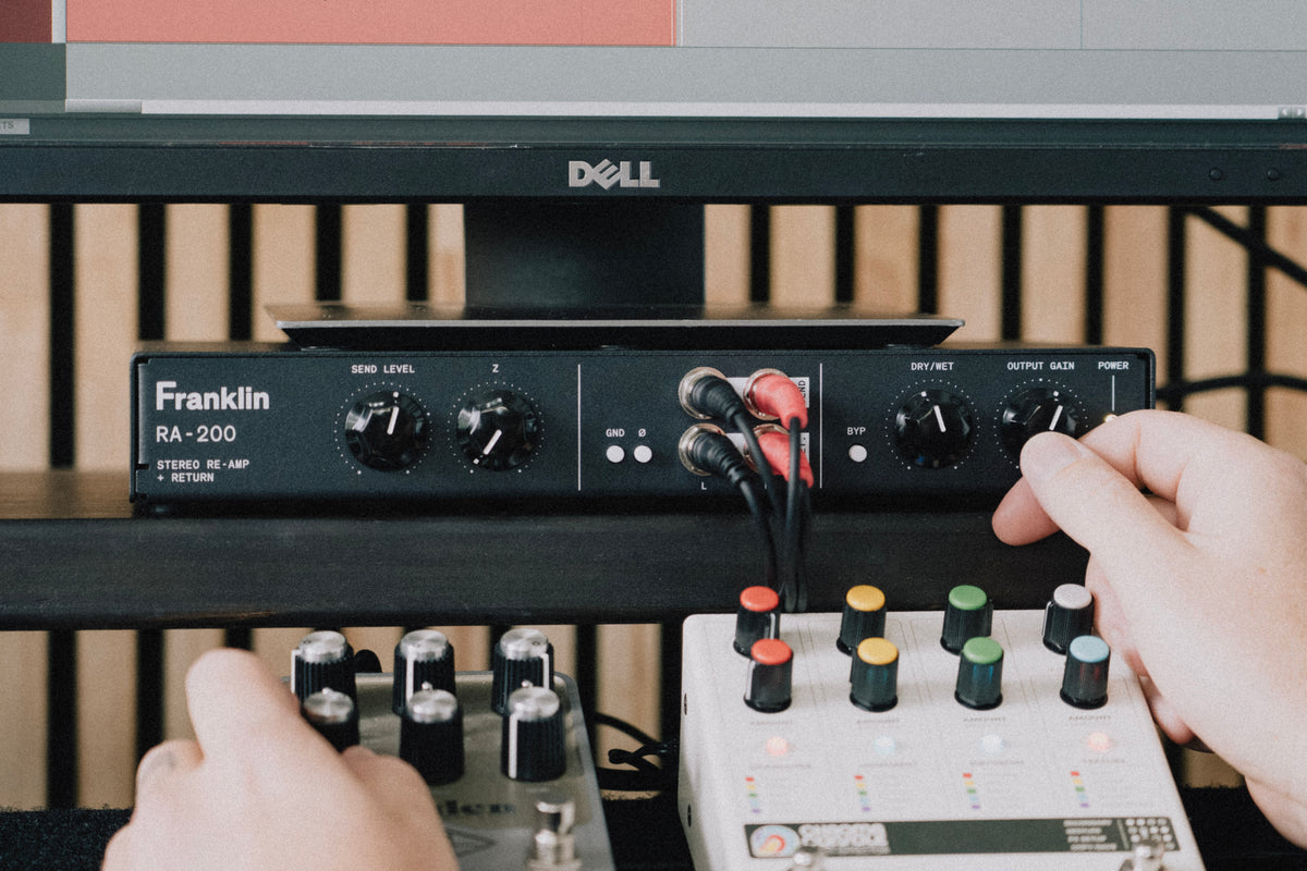 RA-200 on a desk, hands on the front-panel controls with pedals in front
