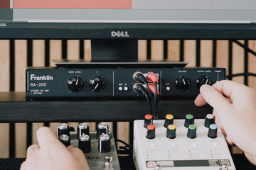 RA-200 on a desk, hands on the front-panel controls with pedals in front