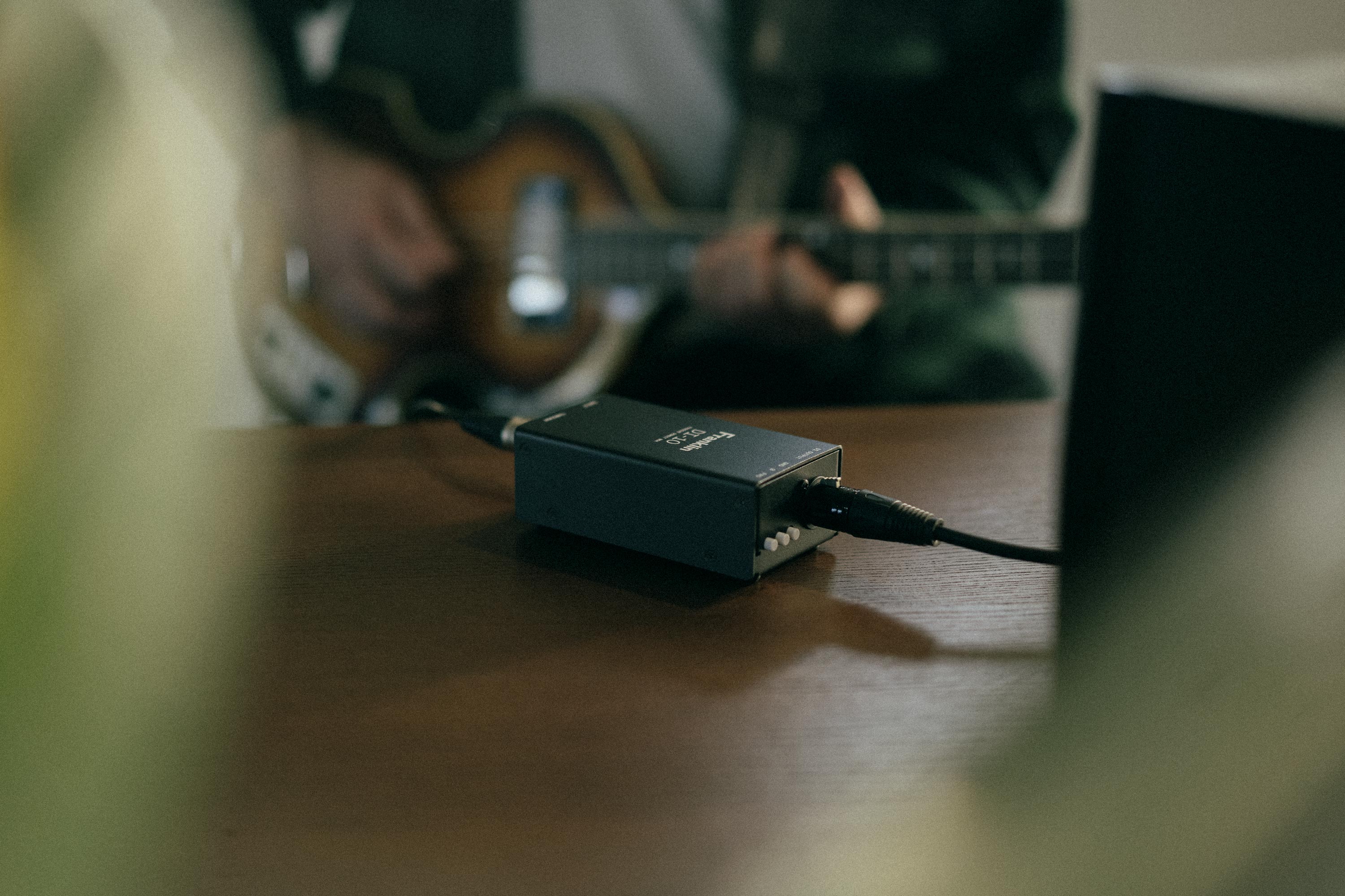 Man playing a bass guitar plugged into a Franklin Audio DI-10 box